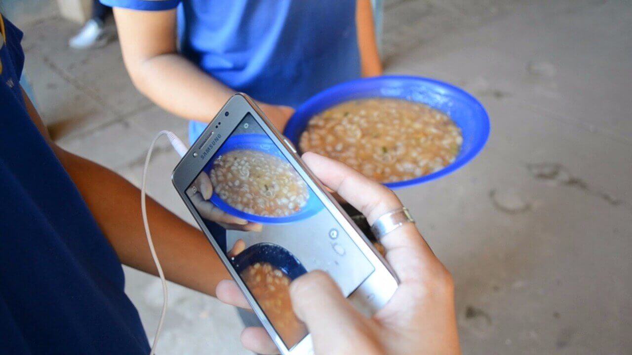 Imagem de adolescentes tirando foto de um prato de alimentado dado pela escola