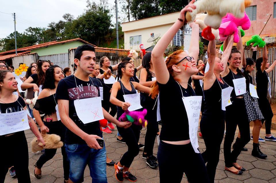 Imagem de adolescentes protestando na rua com cartazes pindurados no pescoço